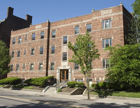 A red brick building with a tree in front of it.