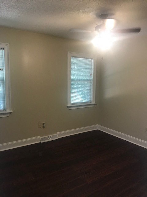 an empty room with a ceiling fan and two windows