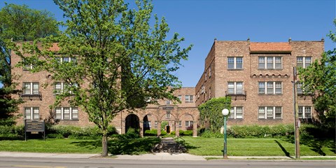A large brick building with a tree in front.