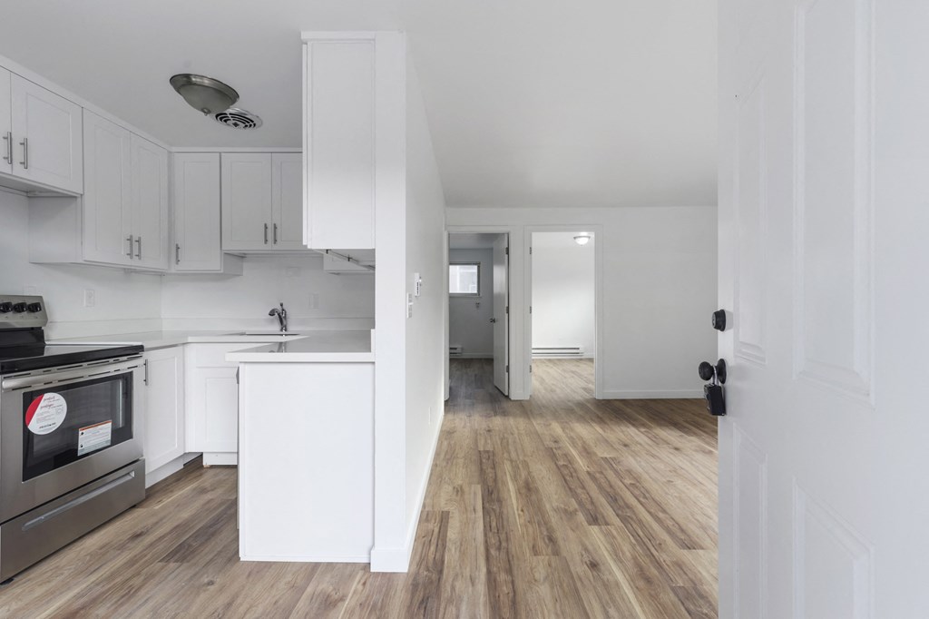 an open kitchen and living room with white cabinets and wood floors