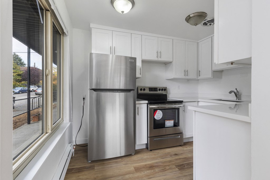 a kitchen with white cabinets and stainless steel appliances and a window