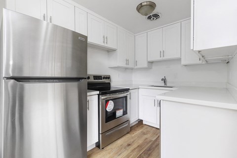 a white kitchen with stainless steel appliances and white cabinets