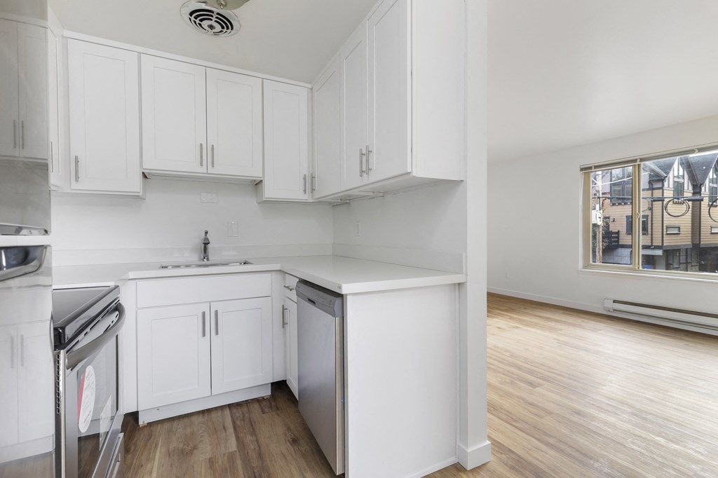 an empty kitchen with white cabinets and stainless steel appliances