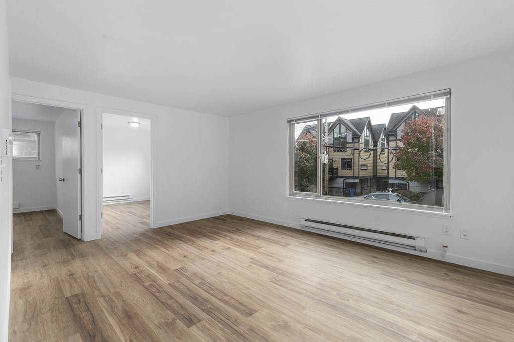 a living room with a large window and hardwood floors