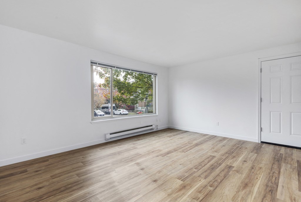 an empty living room with white walls and a large window