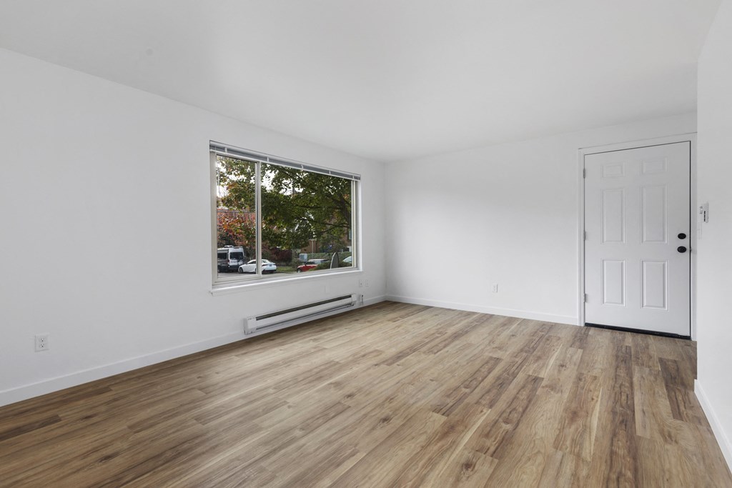 a living room with white walls and a large window and wooden floors