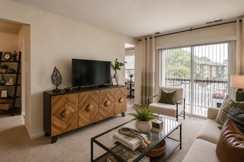 A living room with a glass coffee table and a wooden cabinet.
