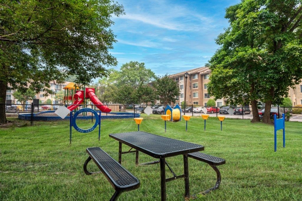 a park with a playground and picnic table in the grass