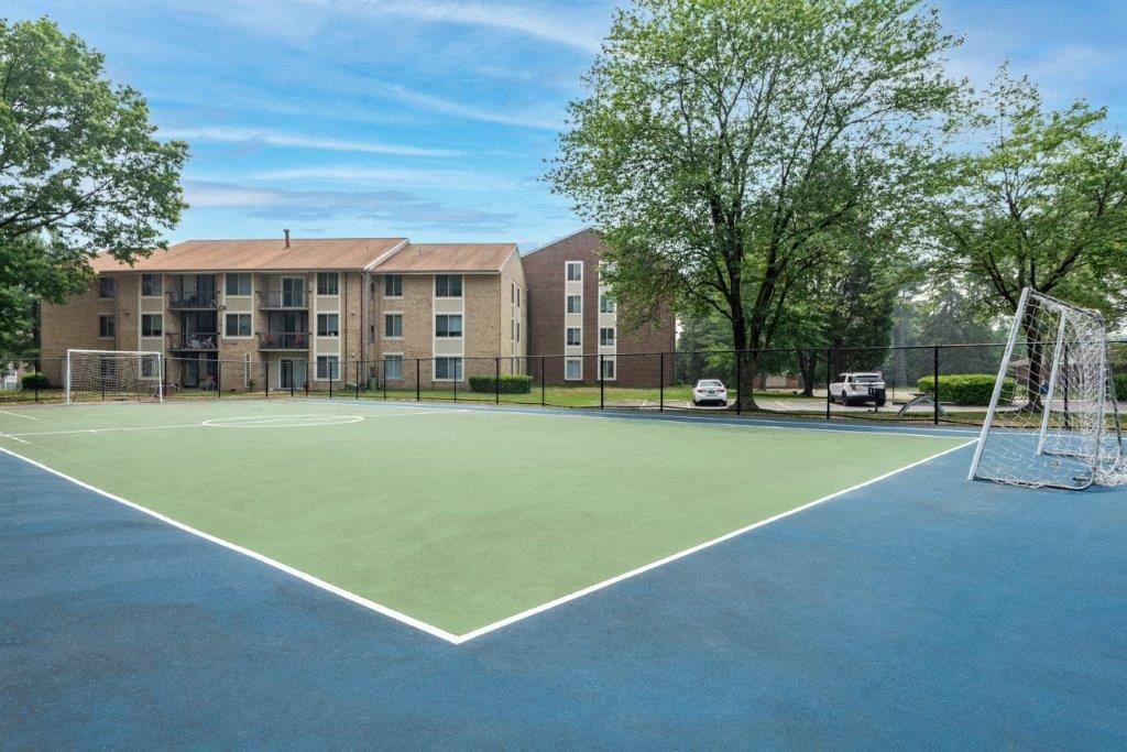 a tennis court with a soccer net in front of an apartment building