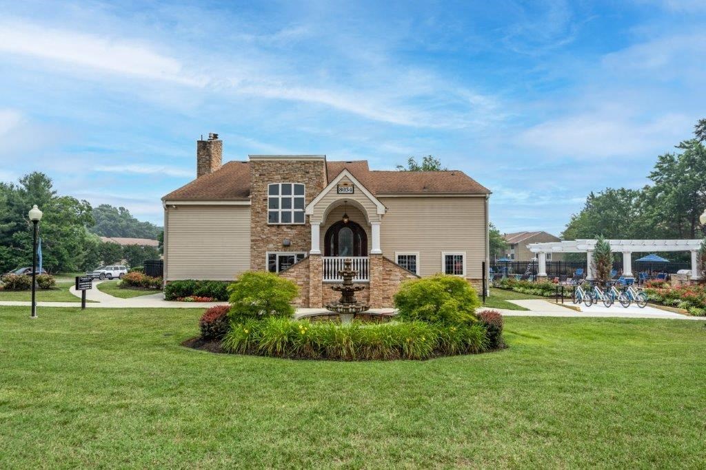 the front of a house with a lawn and a fountain