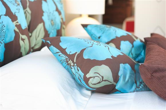 a bed with blue and brown pillows on it