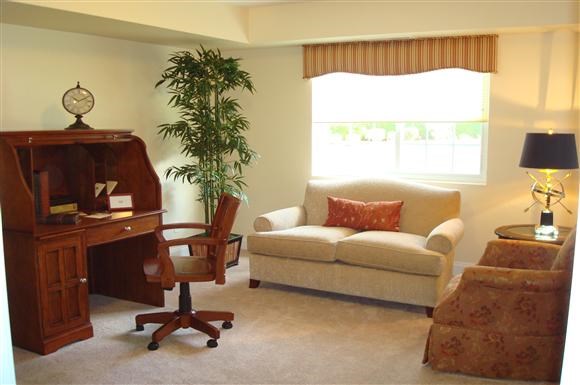 a living room with a couch and a chair and a desk