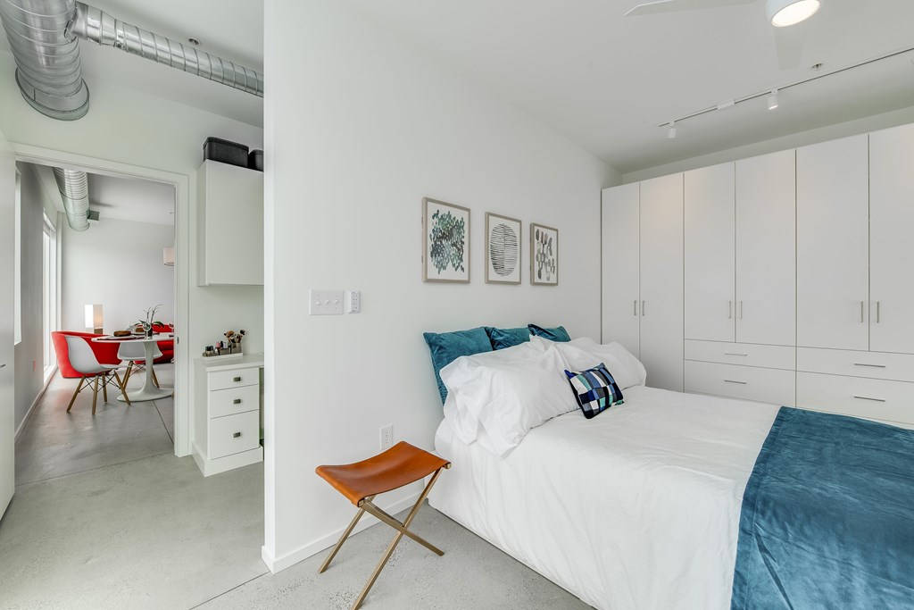 a white bedroom with a white bed and a blue blanket    and a