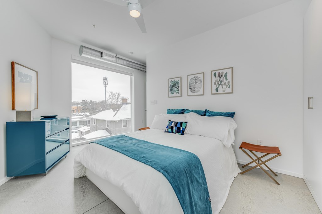 a white bedroom with a large bed and a large window