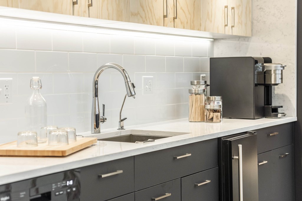 a white kitchen with black cabinets and a stainless steel sink