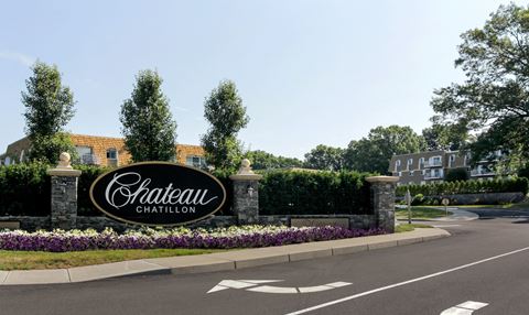 an exterior view of a chateau carillon sign in front of a driveway