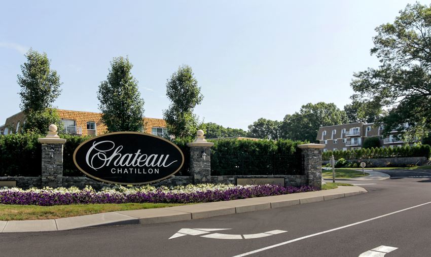 an exterior view of a chateau carillon sign in front of a driveway