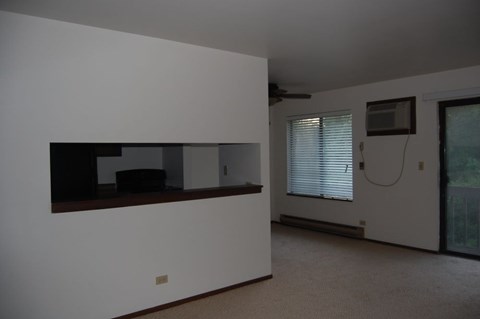 A room with a white wall and a brown shelf.