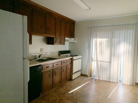 A kitchen with brown cabinets and a white refrigerator.