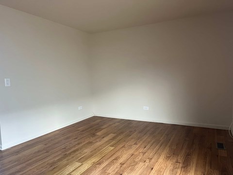 A room with wooden flooring and white walls.