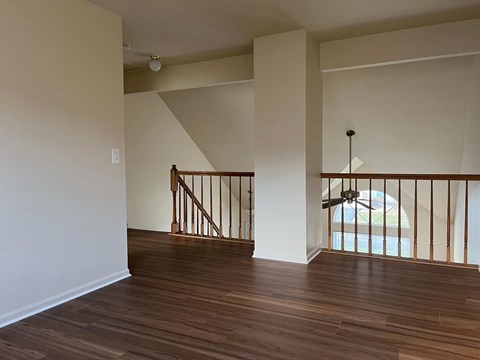 A room with wooden floors and a staircase with a railing.