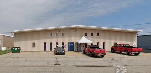 A large building with a white tent in front and two red trucks parked in front.