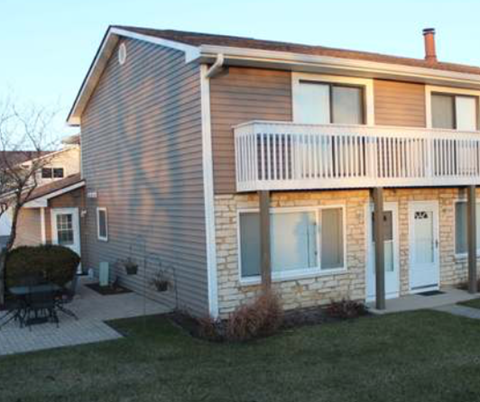 A house with a balcony and a patio with a table and chairs.