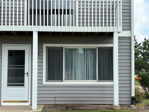 A grey house with a white door and a balcony.