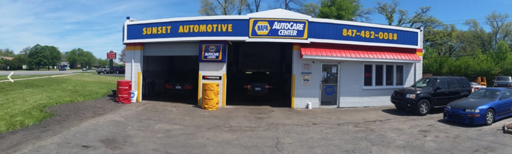 A Sunset Automotive shop with a blue car in front.