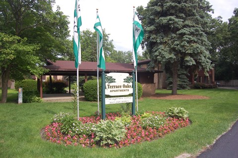 a round flower bed with three flags in front of a sign