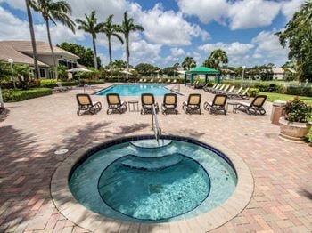 a hot tub with a fountain in the middle of a patio with chairs