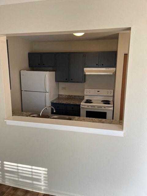 A kitchen with a white fridge and stove top oven.