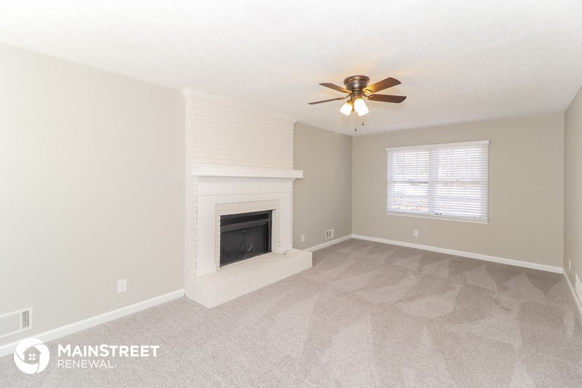 a living room with a fireplace and a ceiling fan