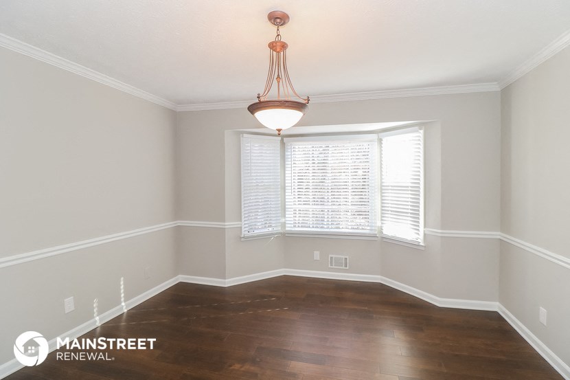 the living room of a home with wood floors and a large window