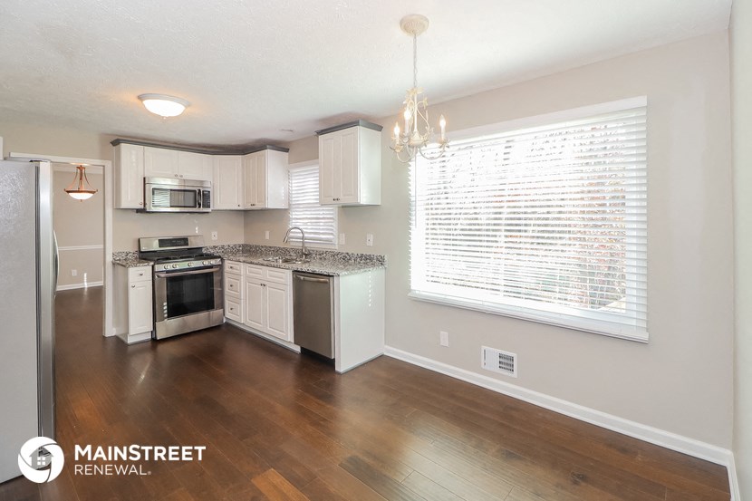an empty kitchen with white appliances and a large window