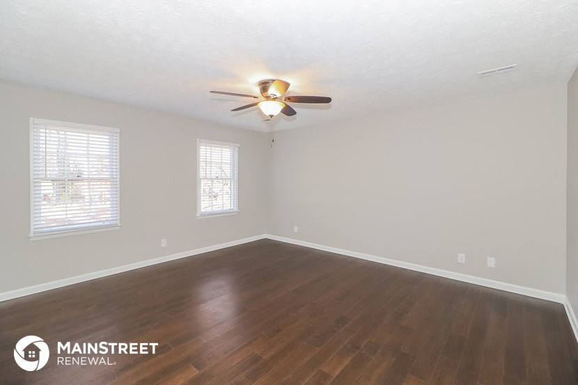 an empty living room with a ceiling fan and wood floors