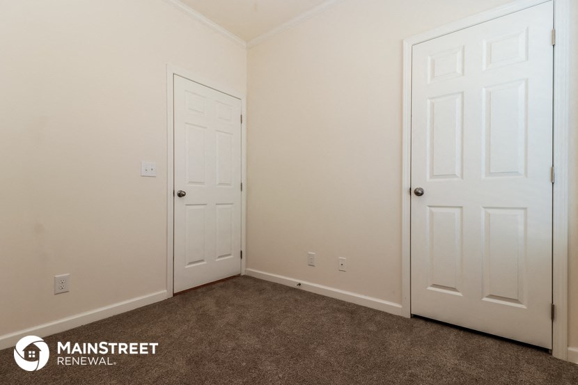 a bedroom with two white doors and a carpeted floor