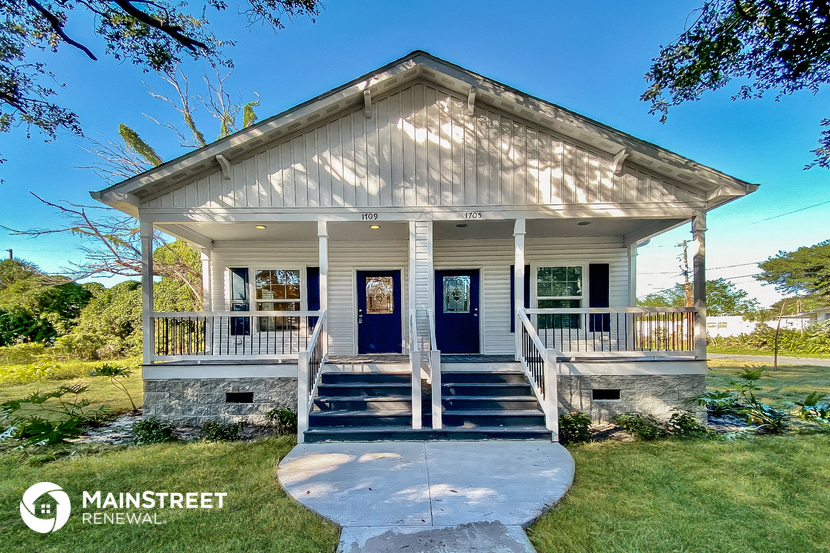 the front of a small white house with a blue door