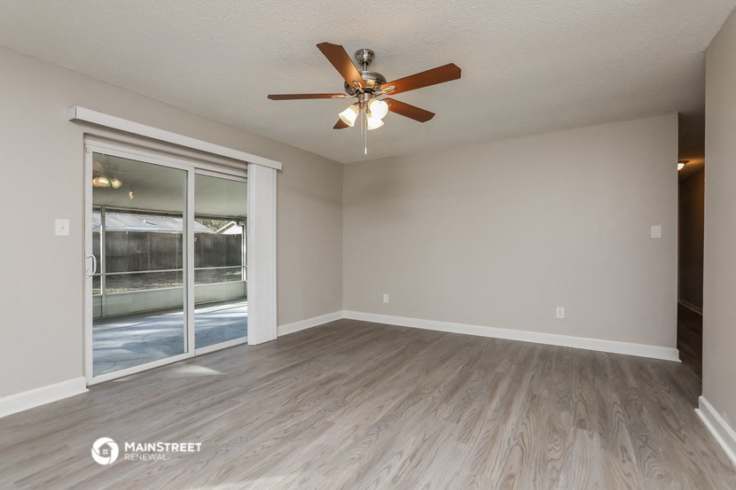 the spacious living room with ceiling fan and wood flooring