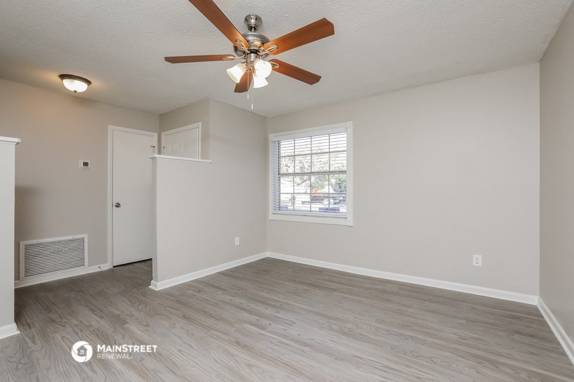 the spacious living room with ceiling fan and wood flooring