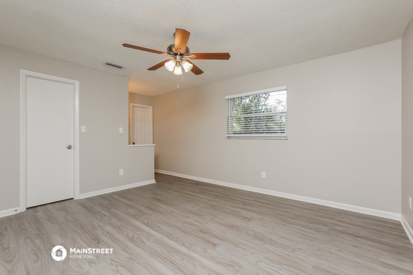 the spacious living room with ceiling fan and wood flooring