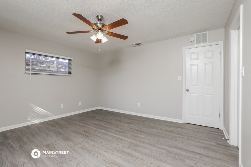 the living room has a ceiling fan and a white door