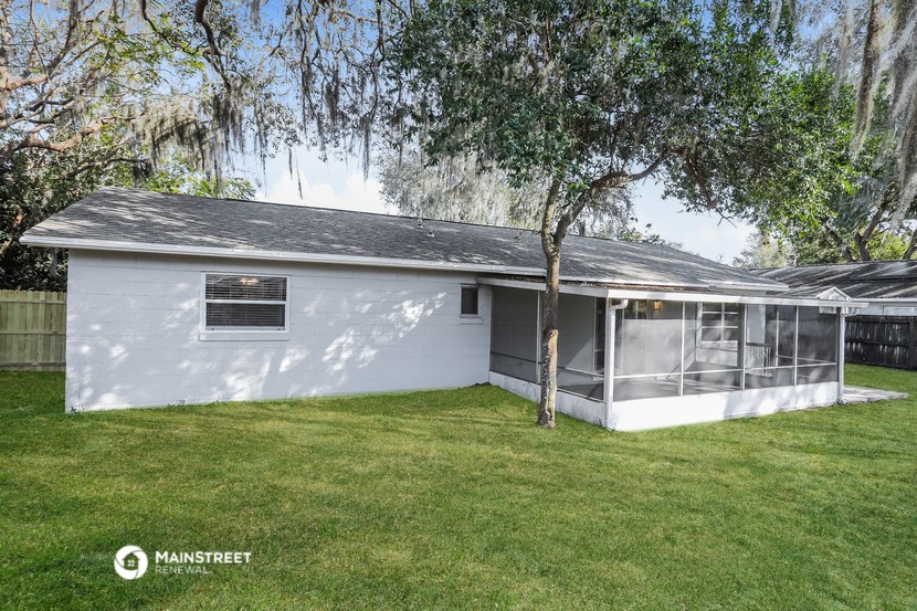 the exterior of a white house with a tree in the yard