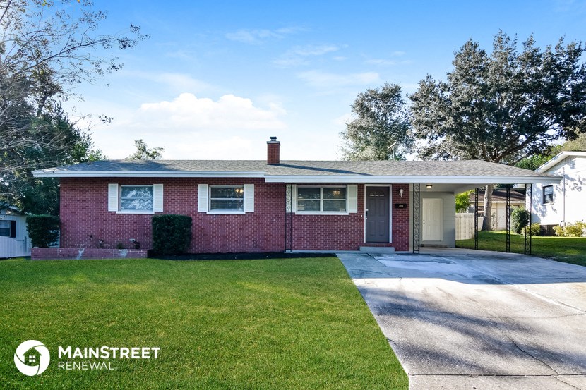 a red brick house with a driveway and lawn