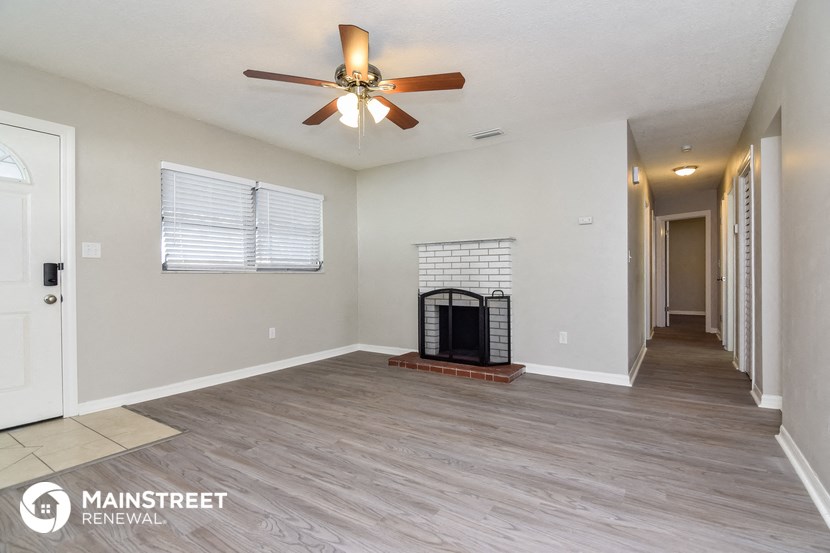 the living room has a fireplace and a ceiling fan
