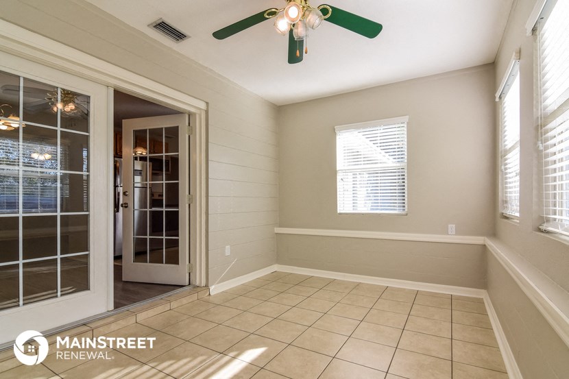 an empty dining room with a ceiling fan and a door to the kitchen