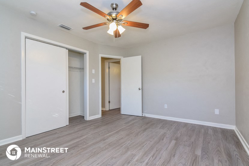 the spacious living room with wood flooring and ceiling fan