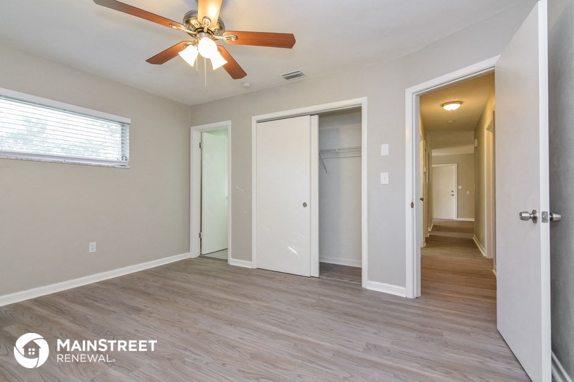 the living room and hallway of an apartment with a ceiling fan