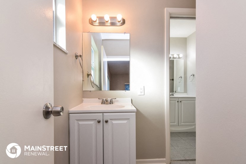 a bathroom with a sink and a mirror and a door to the shower