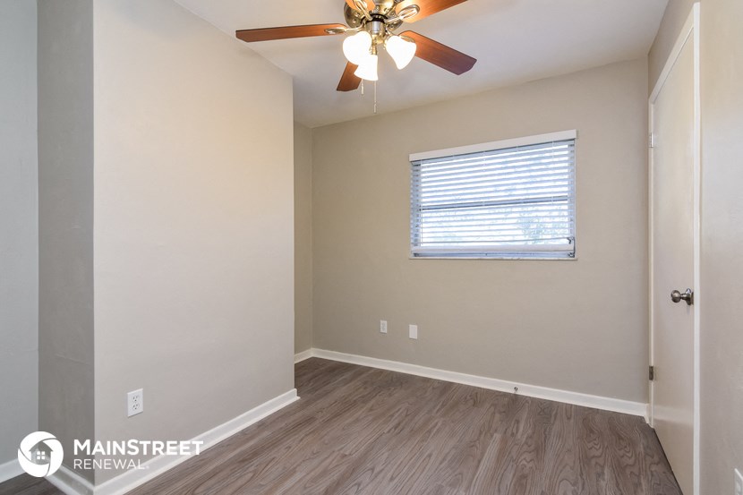 the spacious living room with ceiling fan and wood flooring